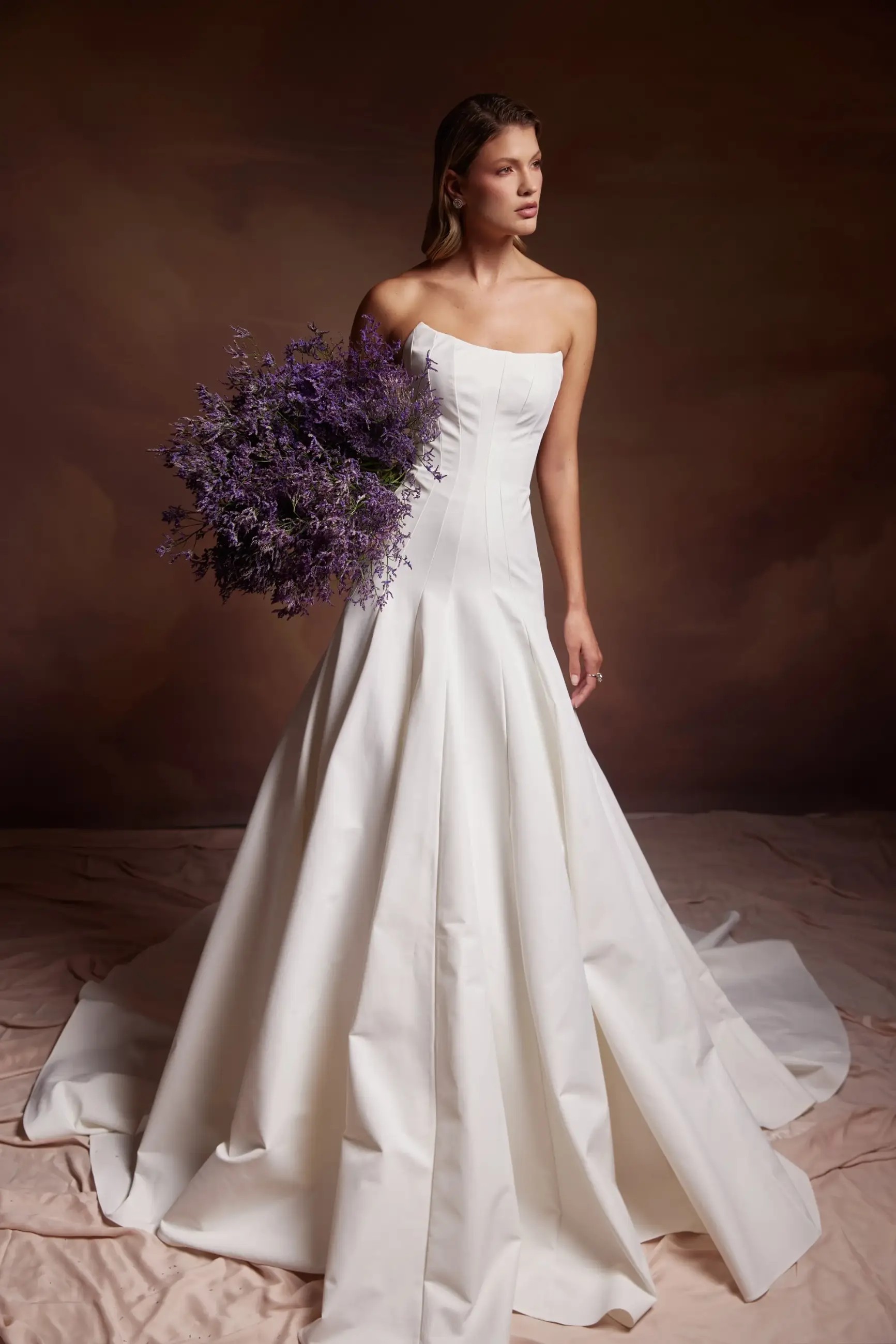 Model is wearing a strapless a-line bridal gown with a dropped waist and full skirt