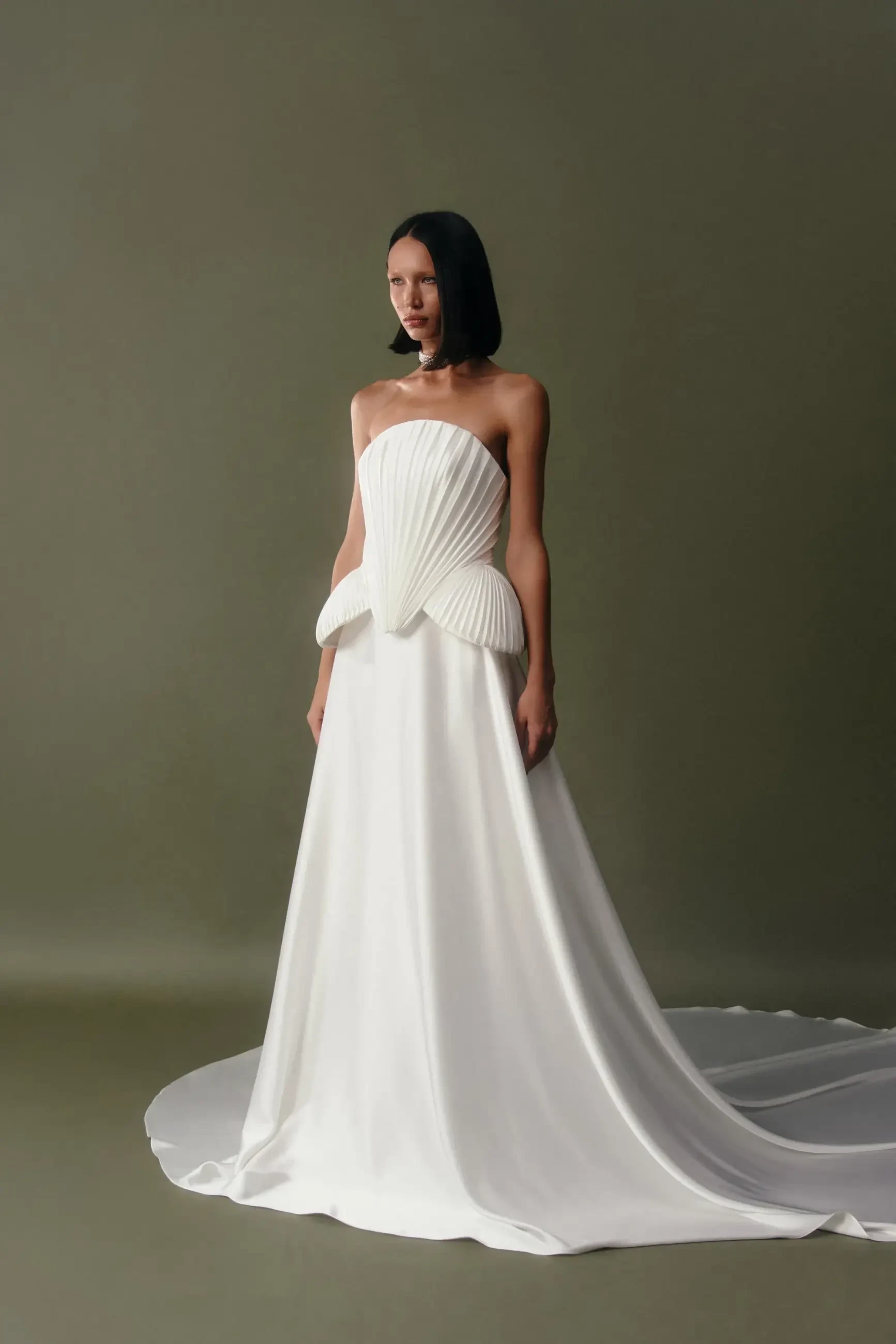 Model is wearing a classic flowy A-line satin skirt wedding gown with a natural waist, soft waistband, and long train.