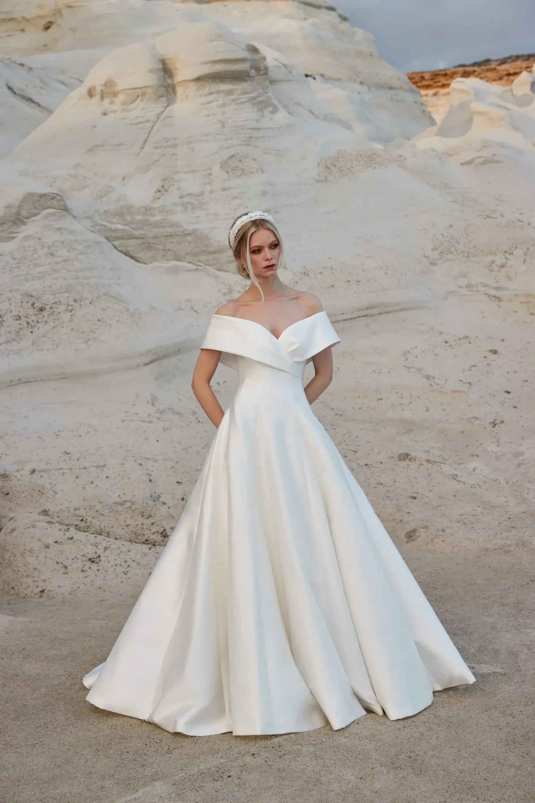 model is wearing an off the shoulder a-line wedding gown