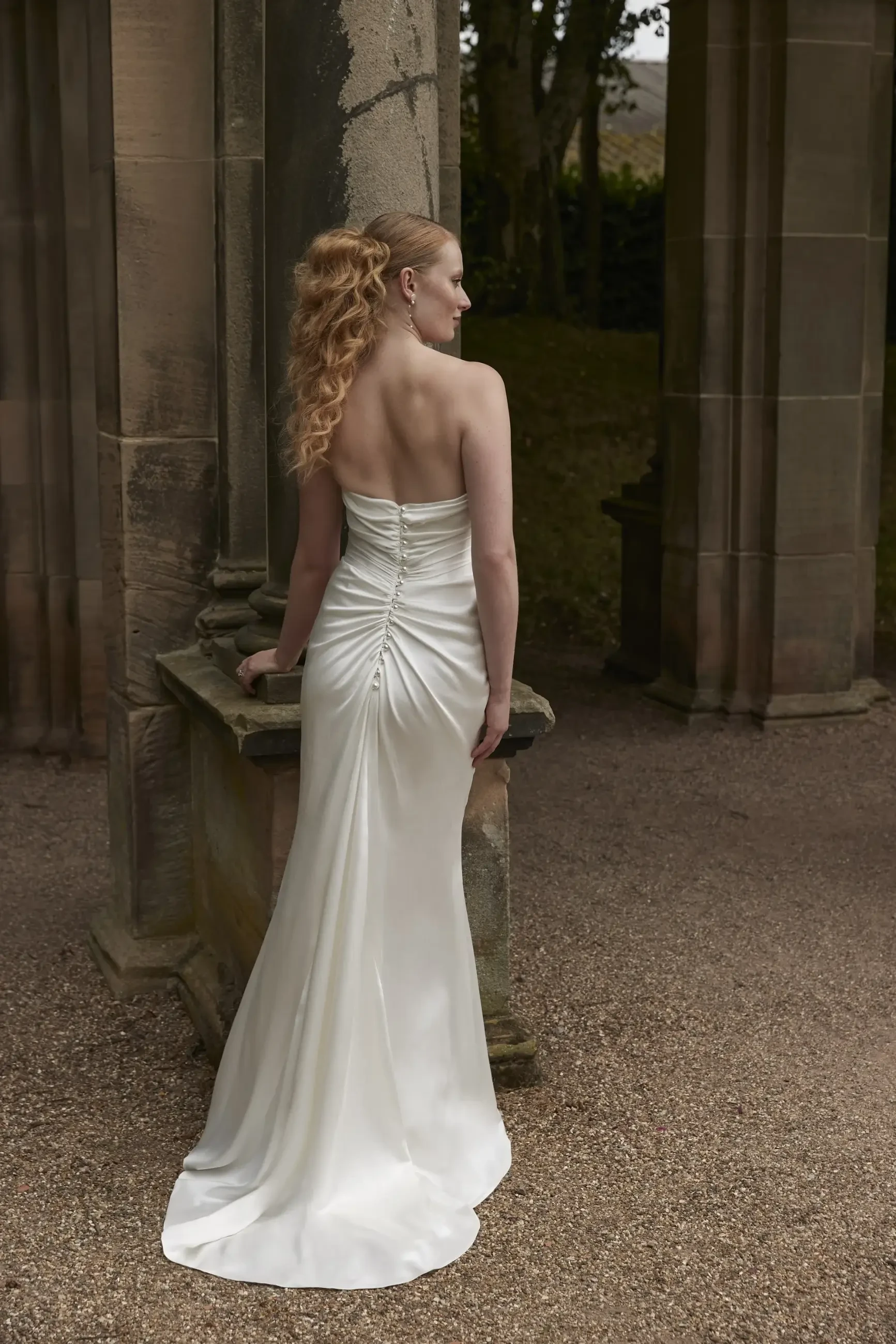 model is wearing a strapless column wedding drress