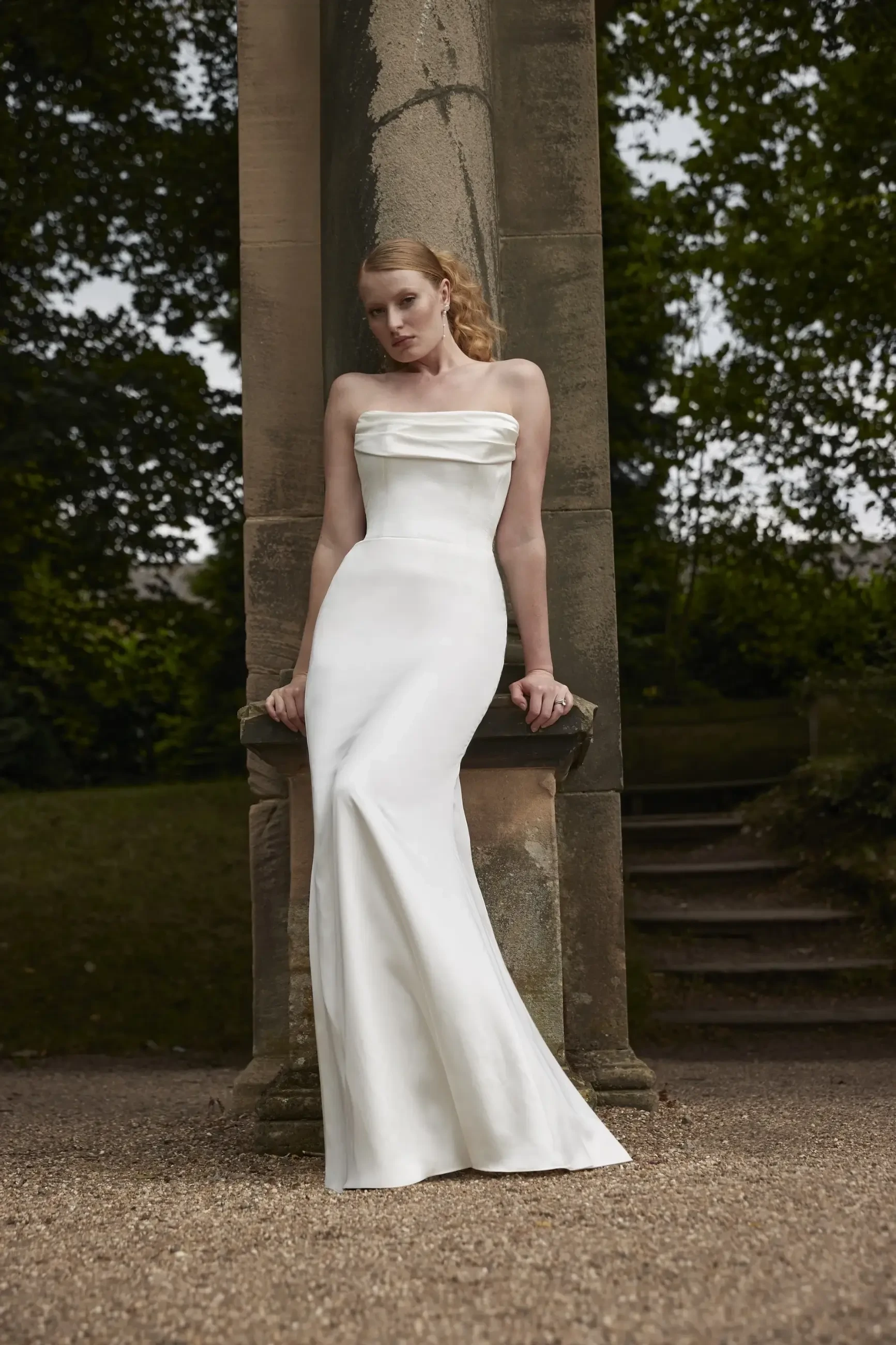 model is wearing a strapless column wedding drress