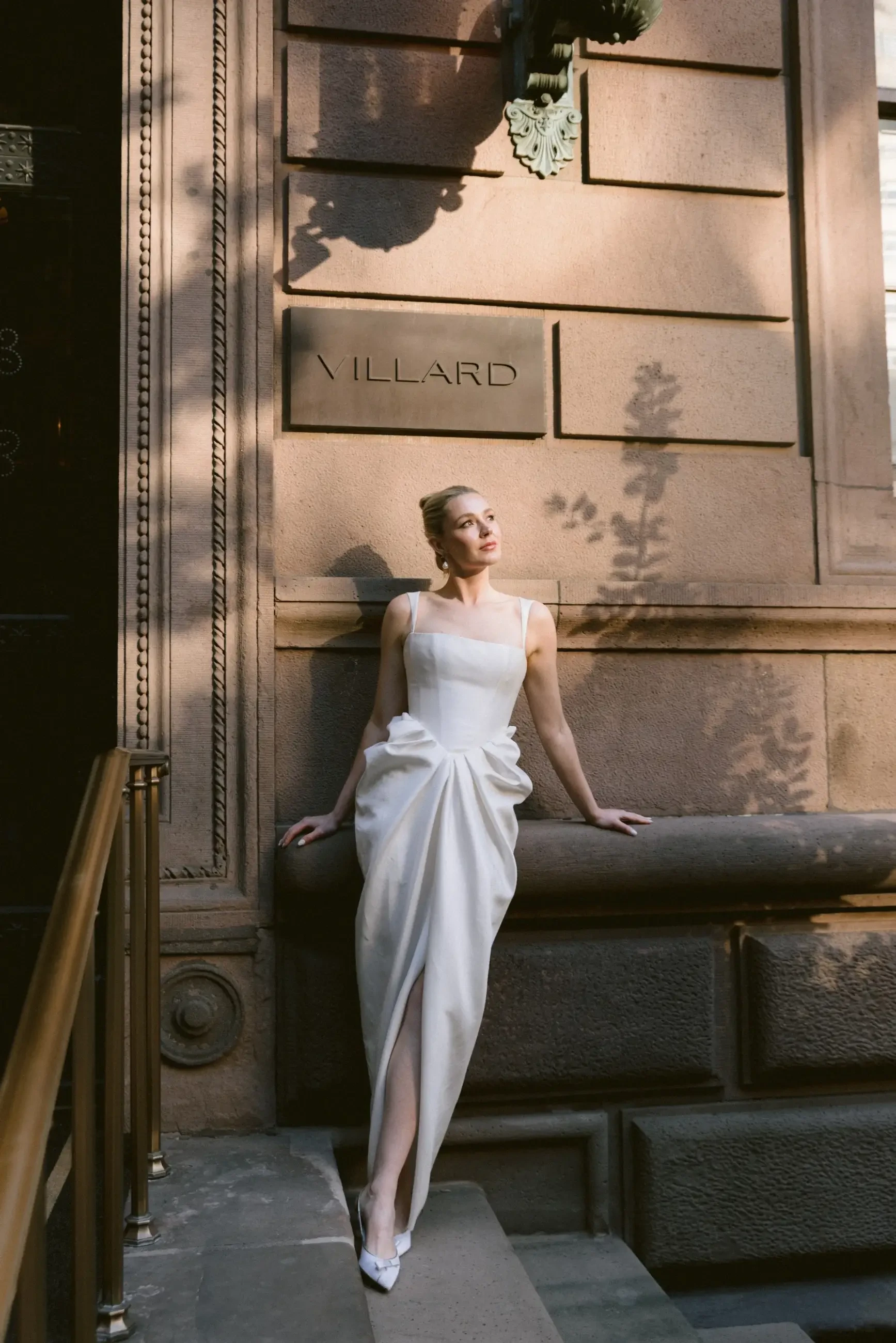 Model is wearing a silk wedding dress with a tulip-shaped skirt and structured basque waist corset.