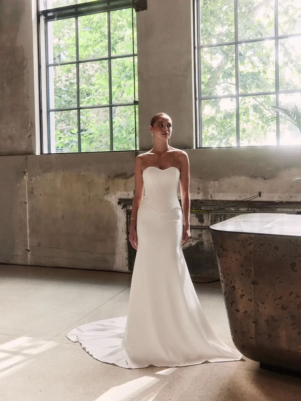 Model is wearing a fit and flare wedding dress with a structured bodice and a dropped waistline 