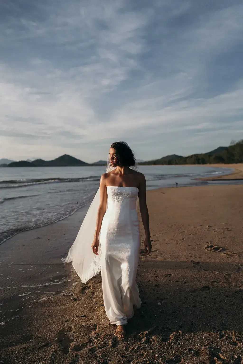 model is wearing a strapless sheath wedding dress